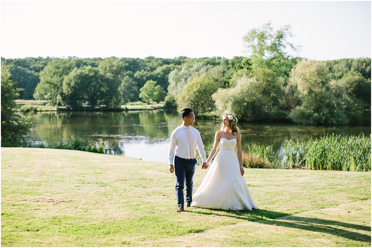 Bride and groom walking alongside a lake