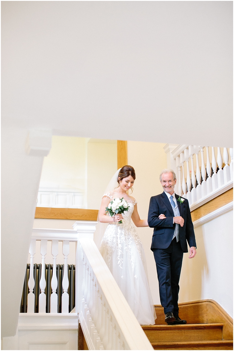 Bride coming down stairs with father