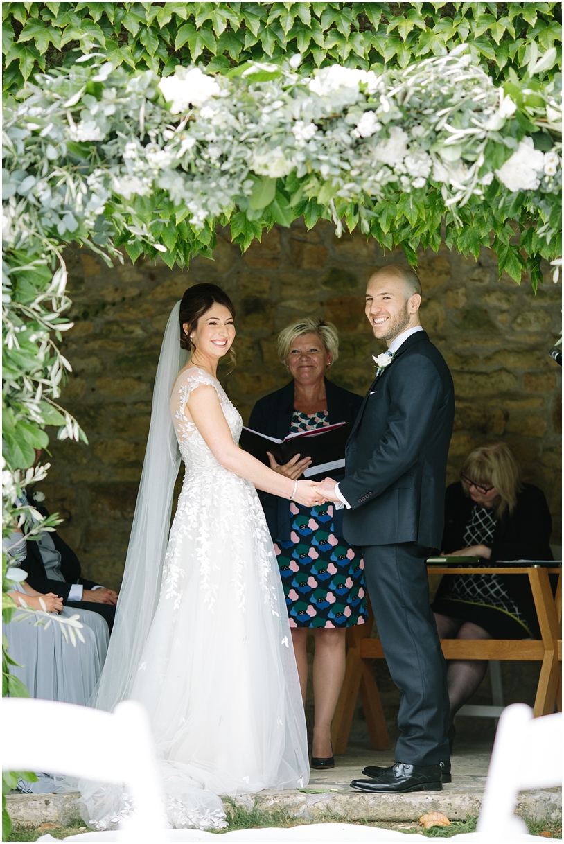 Bride and groom under flower arch