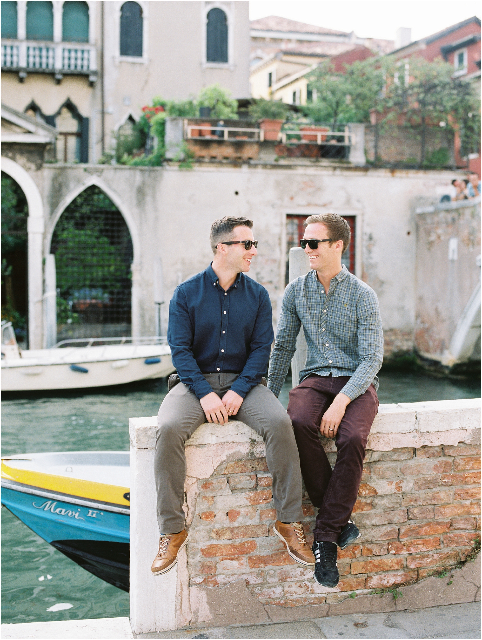 Same sex couple sitting on wall in Venice Italy
