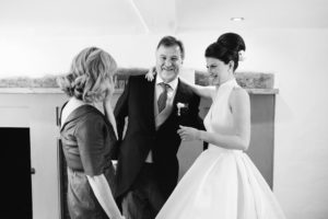 Bride smiling with her mother and father on the morning of her wedding