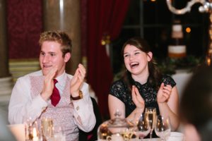 Guests laughing and clapping during speeches at Goodwood House wedding