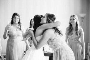 Bride hugging bridesmaid and smiling