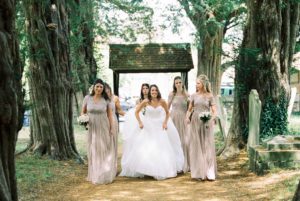 Bride walking with bridesmaids up the path of the church before wedding ceremony