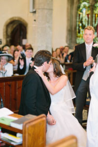 Bride and groom having first kiss in church