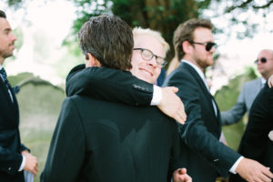 Groomsman hugging groom after wedding ceremony