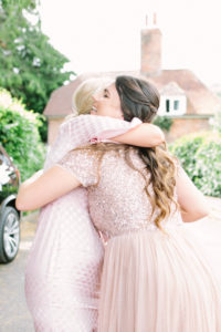 Bridesmaid in blush sequin dress hugging a wedding guest