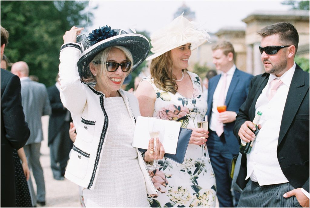Mother of the bride holding hat on wedding day at Stansted House, West Sussex