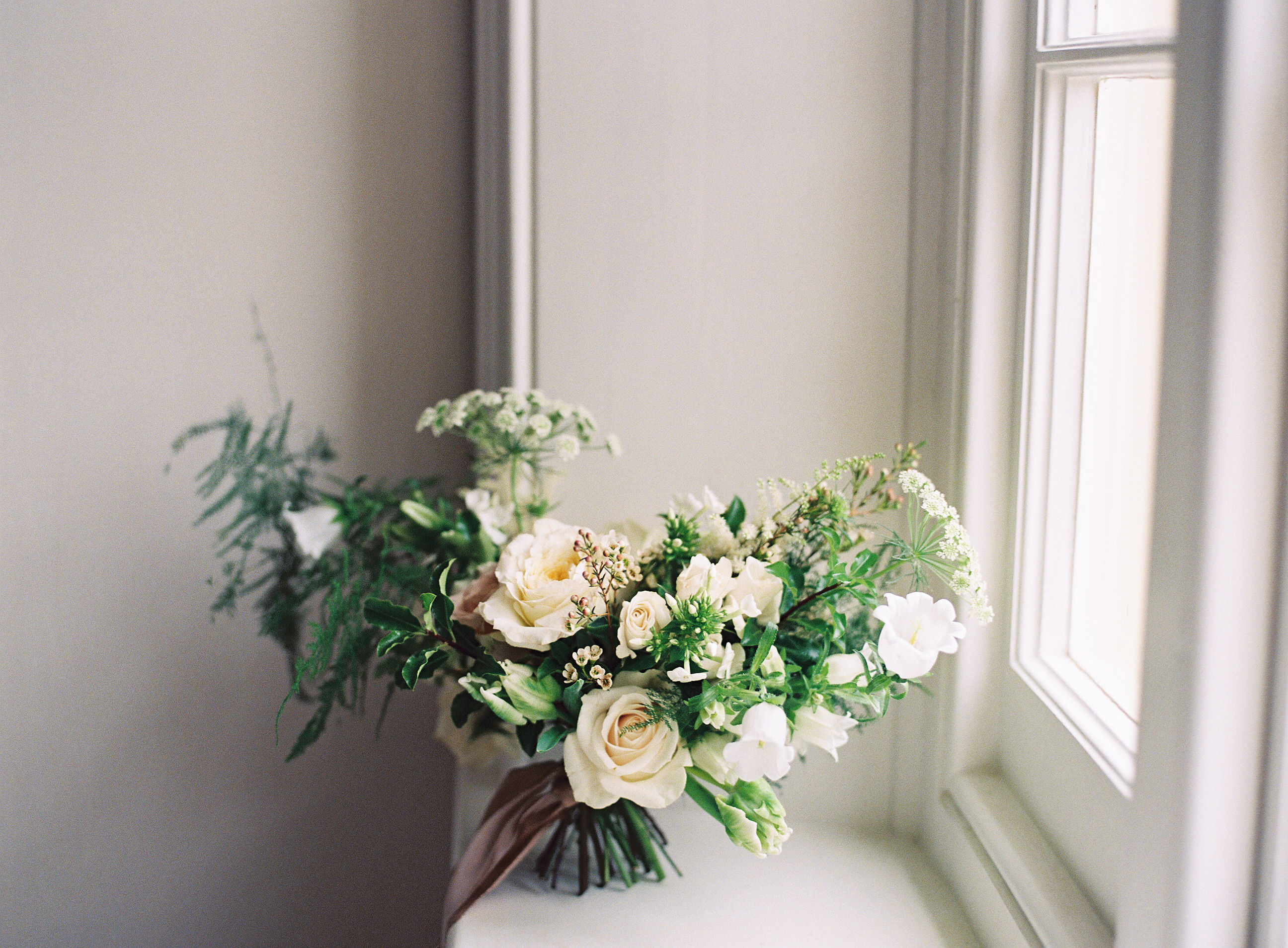 Loosely structured wedding bouquet of blush, cream and green on windowsill at Thorpe Manor luxury wedding venue