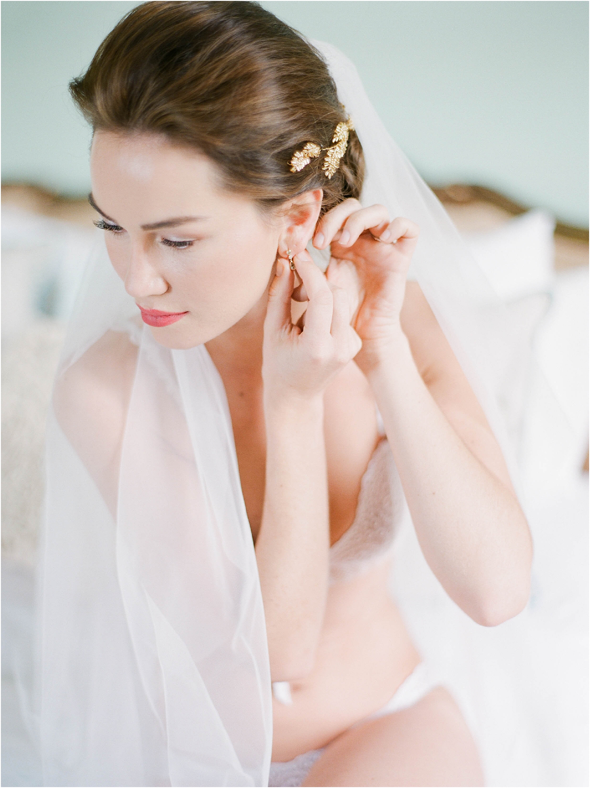 Bride putting in earrings on wedding morning at Hill Place Hampshire