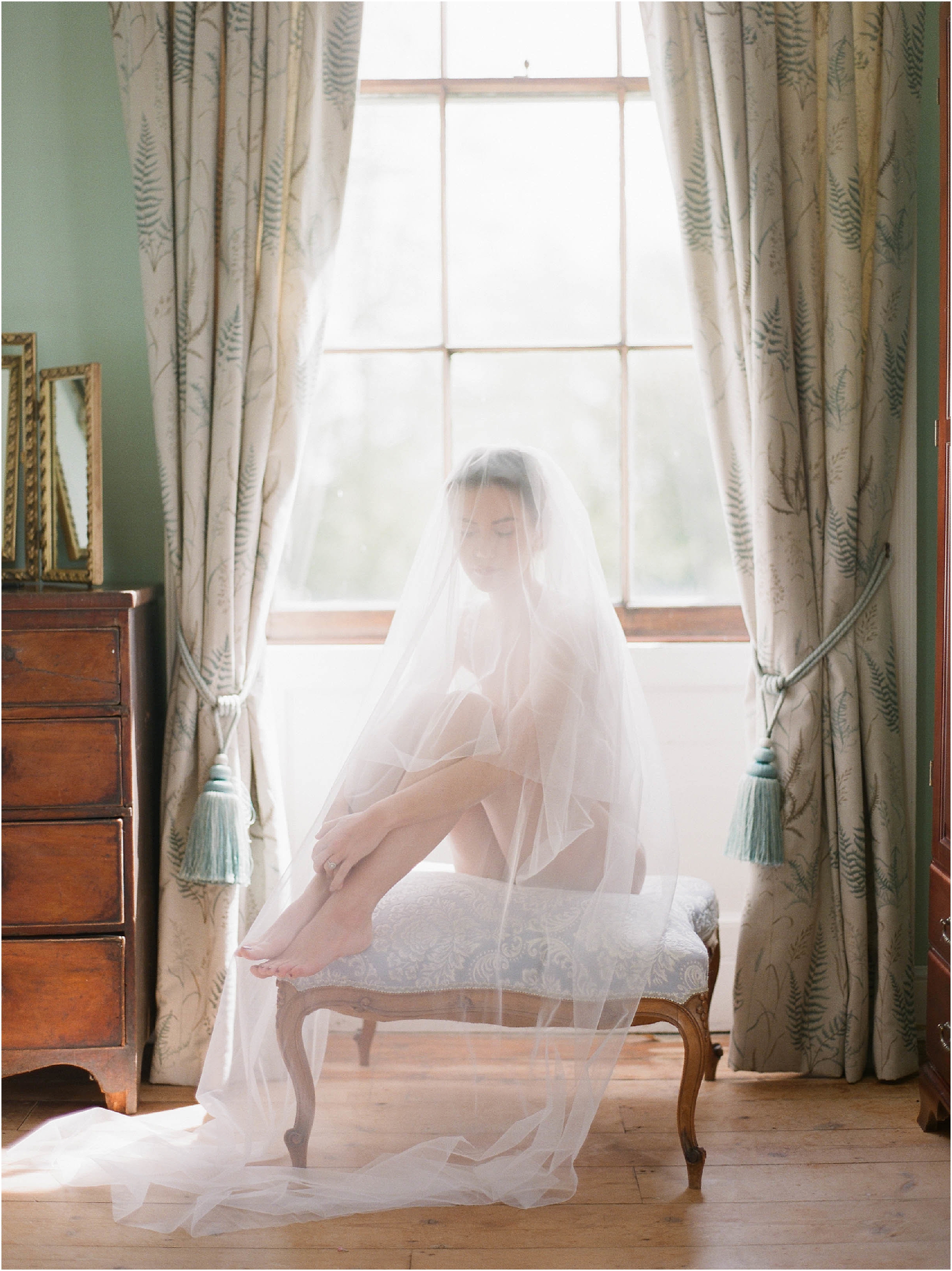 Bride sitting on stool with veil over her