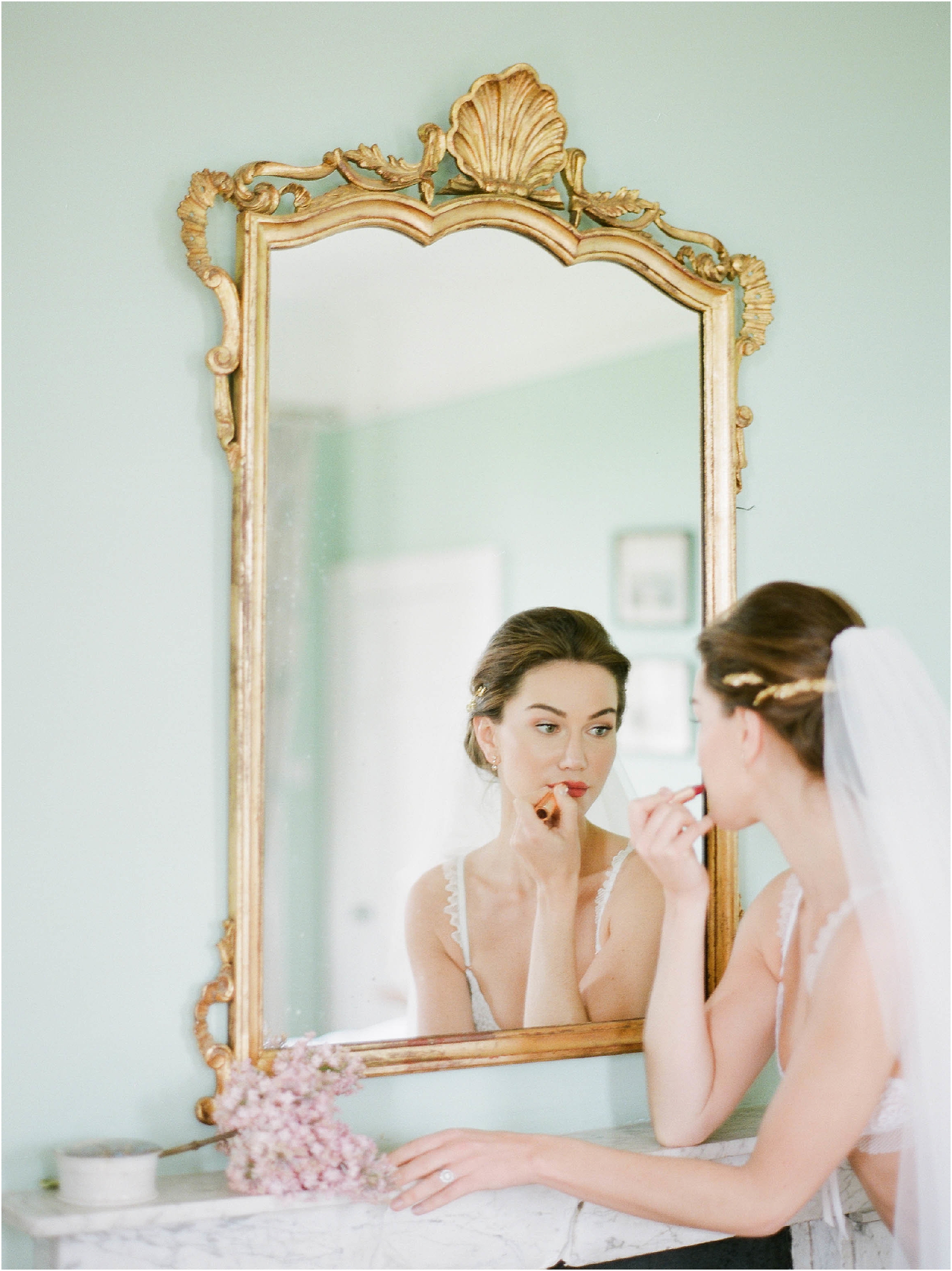 Bride applying lipstick in mirror at Hill Place