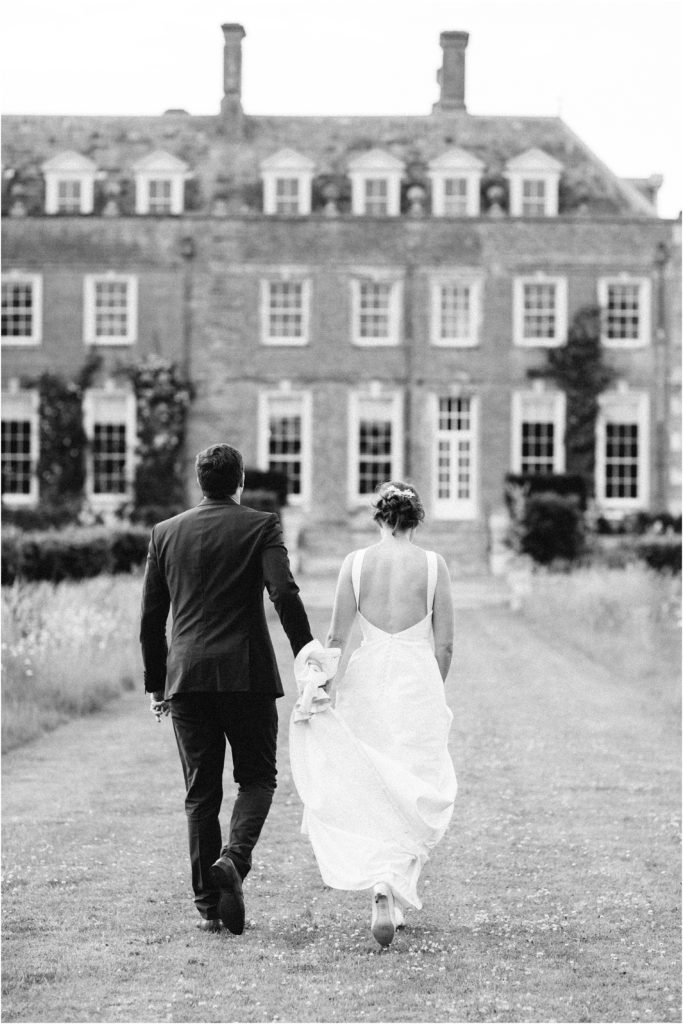 Bride and groom walking away at St Giles House wedding