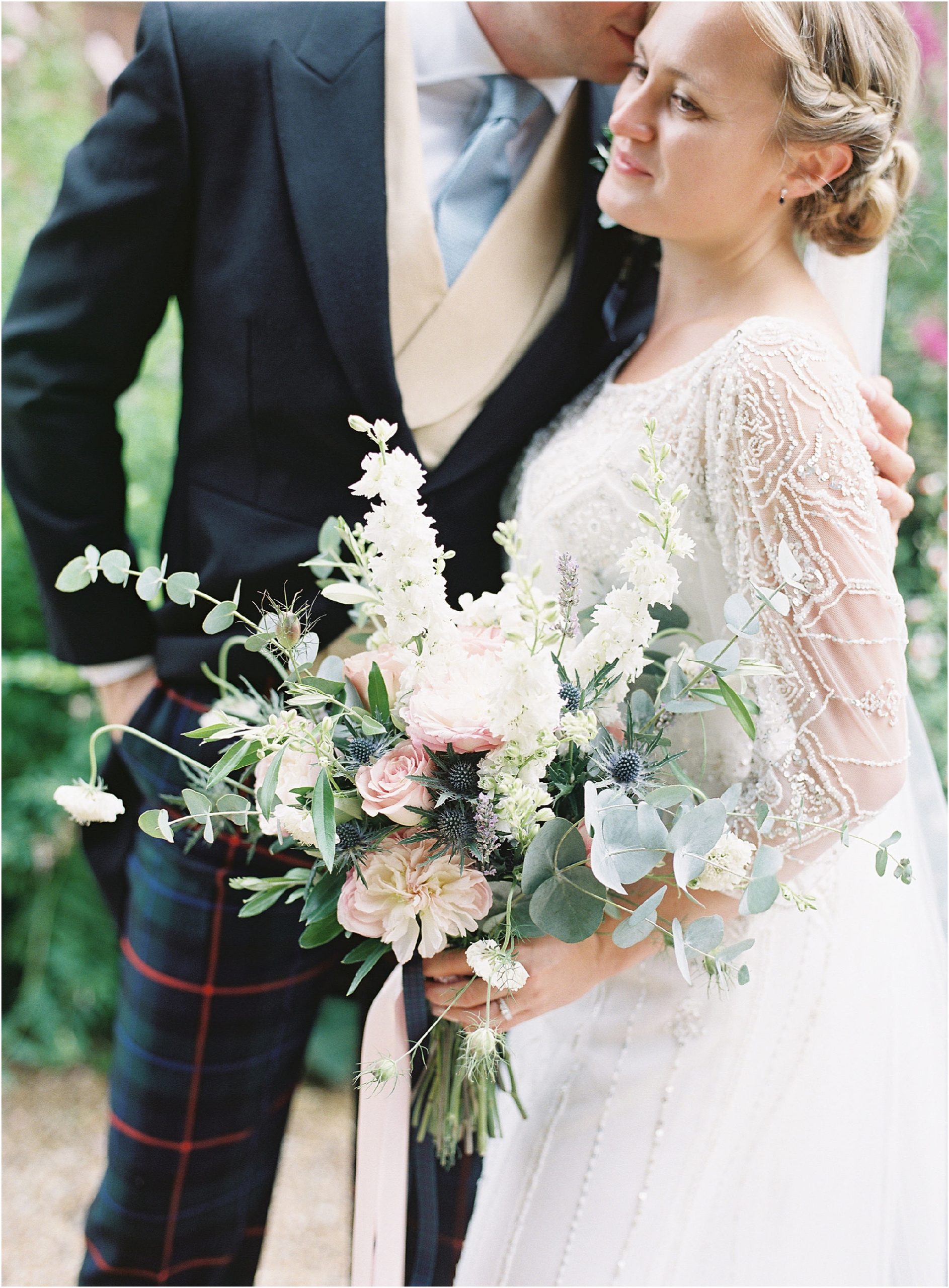 Bride and groom cuddling and holding a wildflower bouquet