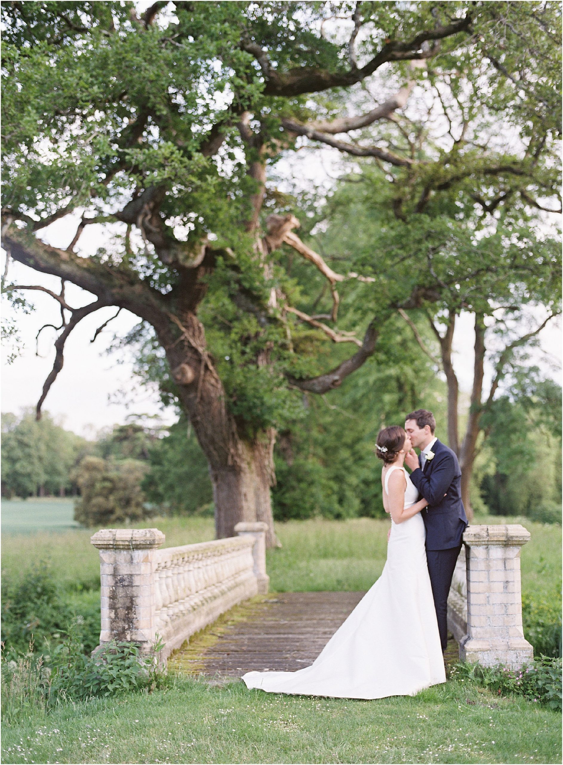 bride and groom kissing on the bridge in the grounds of St Giles House. Fine art wedding photographer Dorset