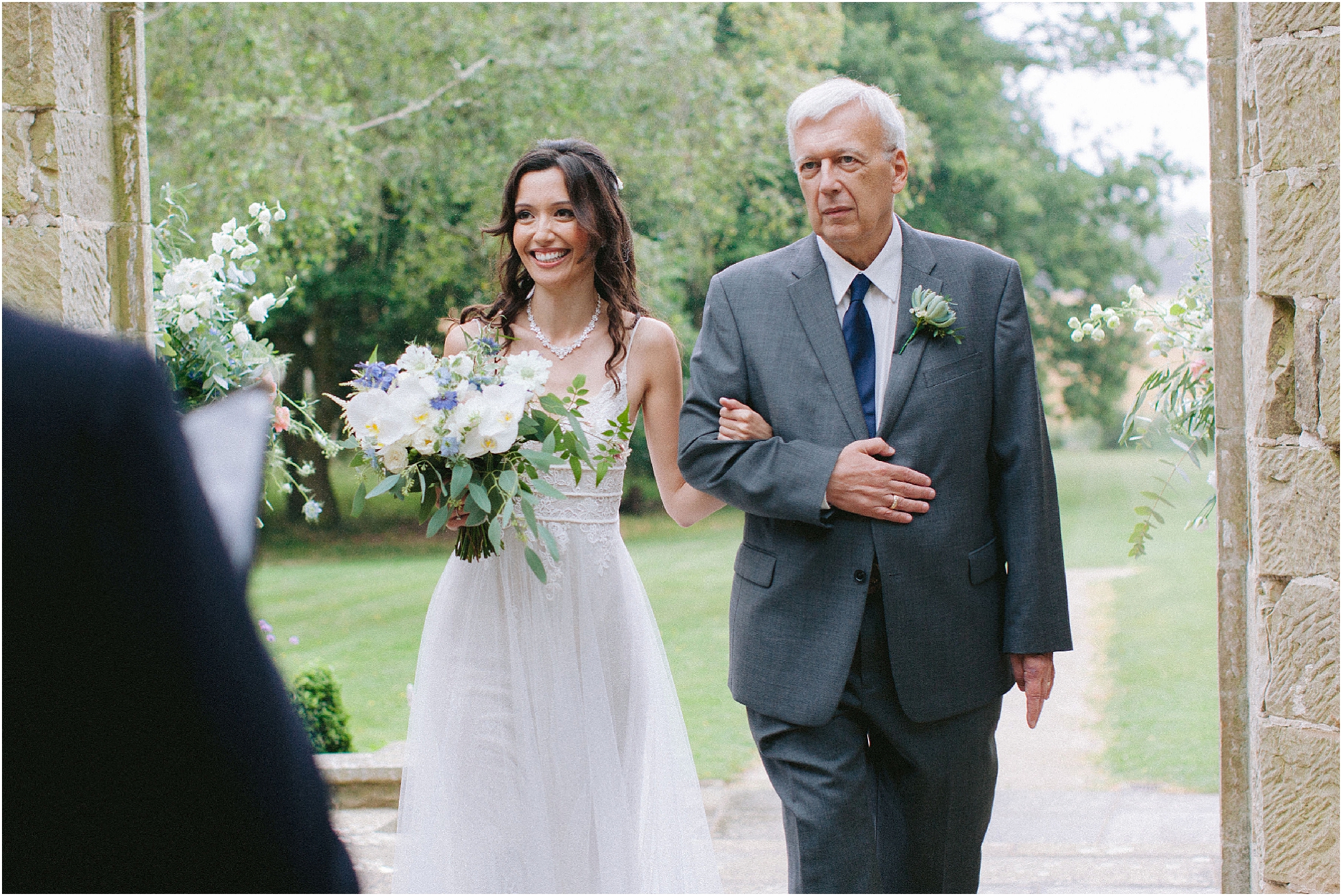 Bride walking into wedding ceremony escorted by her father at Chiddingstone Castle wedding