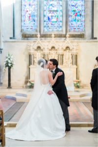 Bride and groom having first kiss at Boxgrove Priory wedding