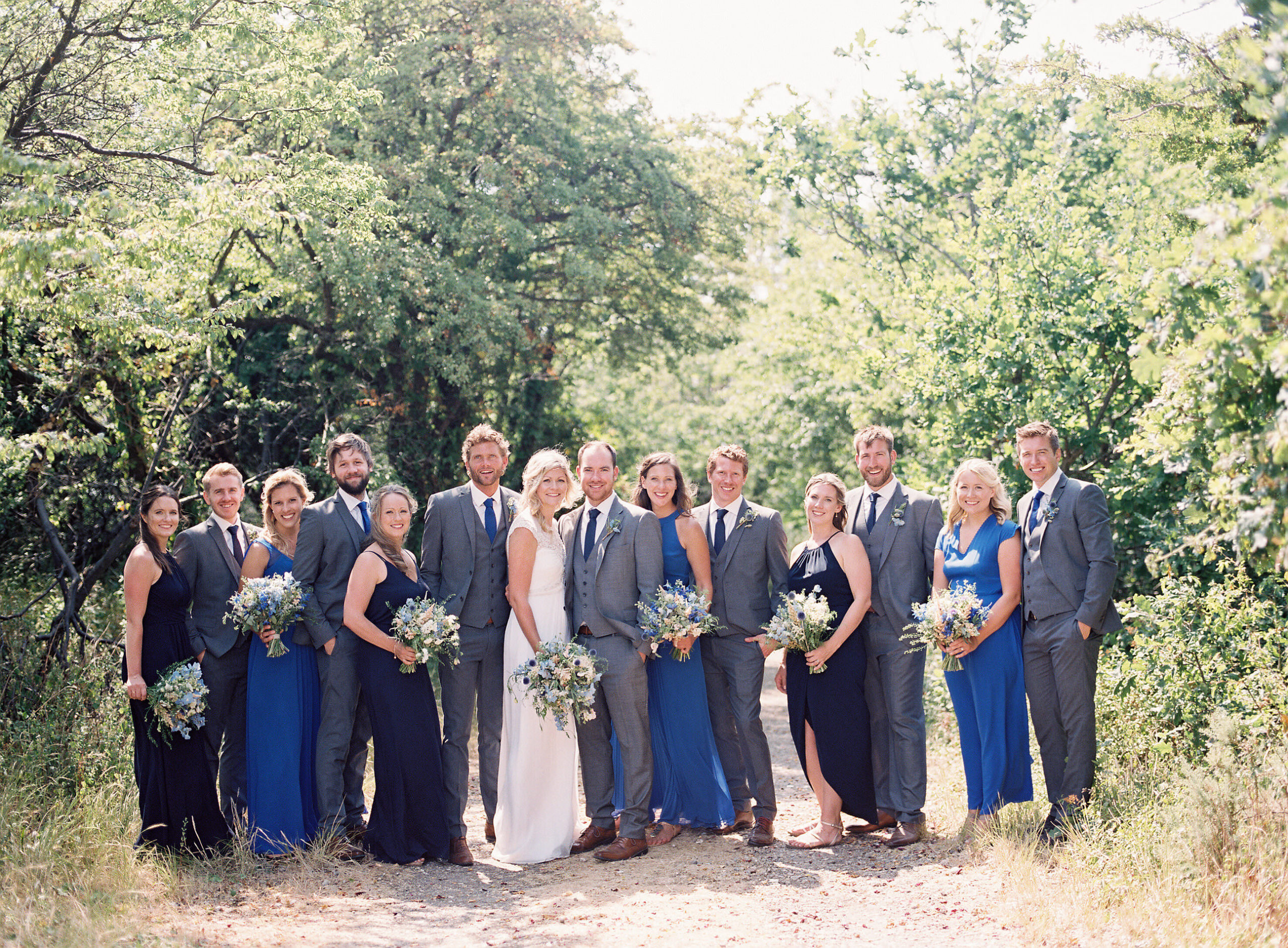 bridal party standing on a dusty path for group photo