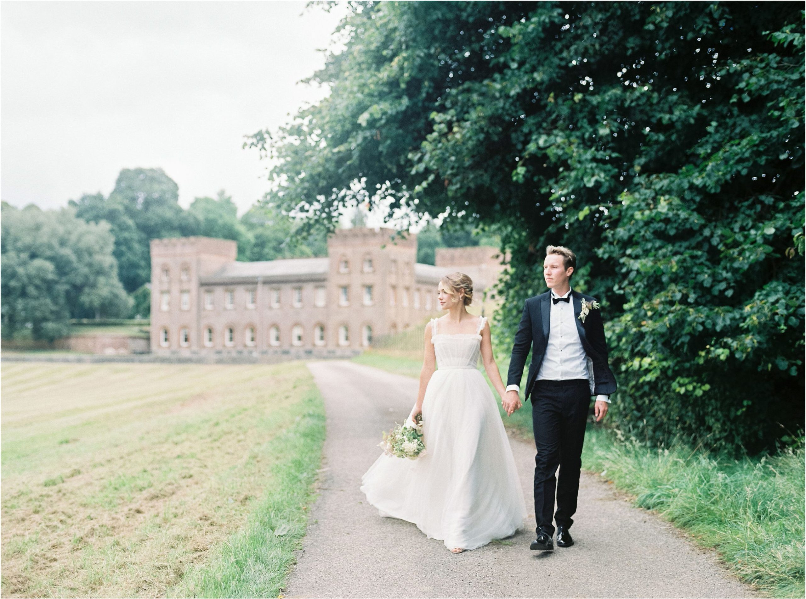 Bride and groom walking away from Ugbrooke House