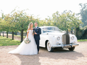 bride and groom with white Rolls Royce at Cowdray House wedding