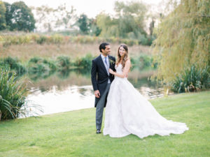 Couple photographs by lake at Ardington House in Monique Lhuillier dress