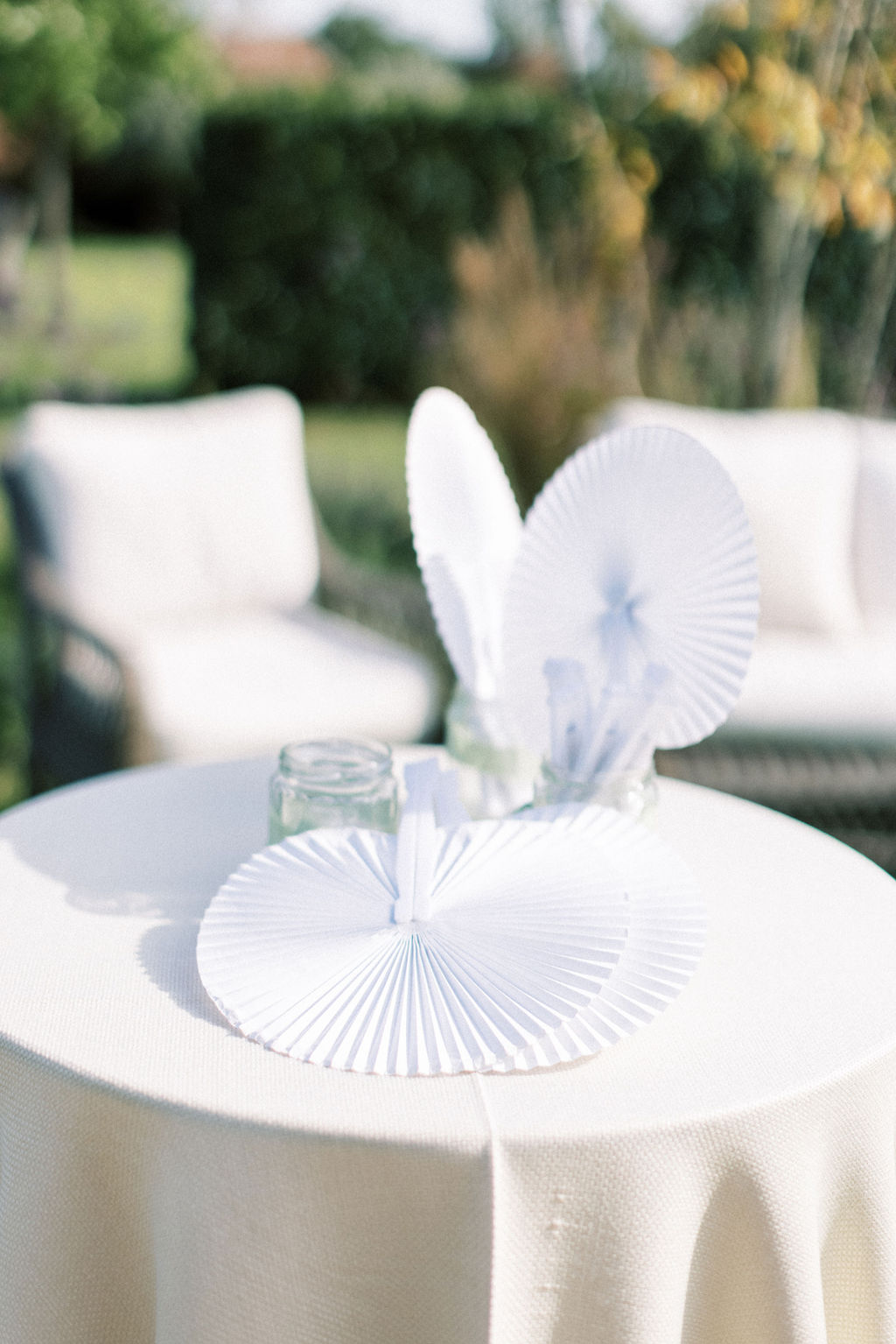 white paper fans on table at garden marquee wedding