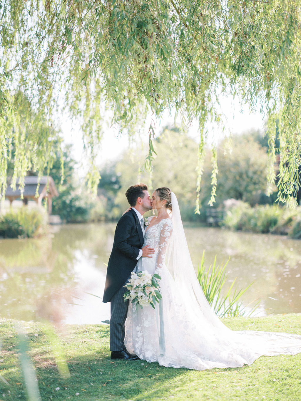 Bride and groom kissing by lake english garden marquee wedding